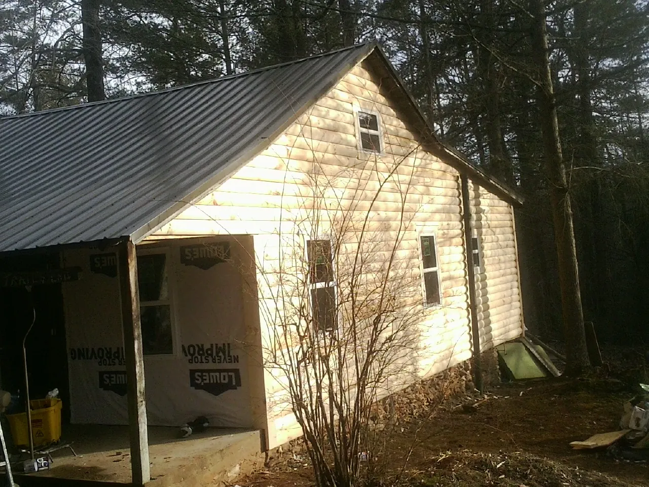 Log siding gable end under a dark metal roof edge in Massapequa Park