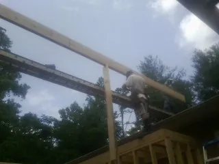 Carpenter setting a ridge beam over a new addition frame — Ice Dam Removal by Roofing Brothers in Massapequa Park