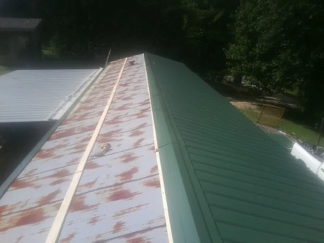Old rusted panels beside newly installed green metal roofing — Wind Damage Roof Repair by Roofing Brothers in Massapequa Park
