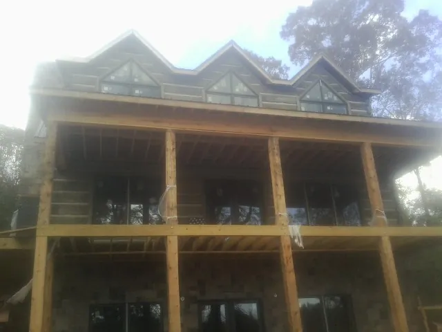 Dormers and porch framing on a large log home under construction — Roof Coating work by our crew in Massapequa Park