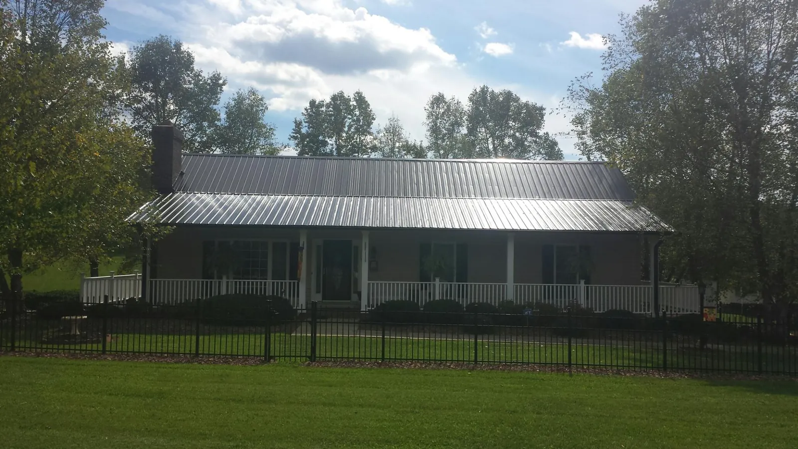 Gray metal roof on a brick ranch with a full width front porch — Gutter Guard Installation work by our crew in Massapequa Park