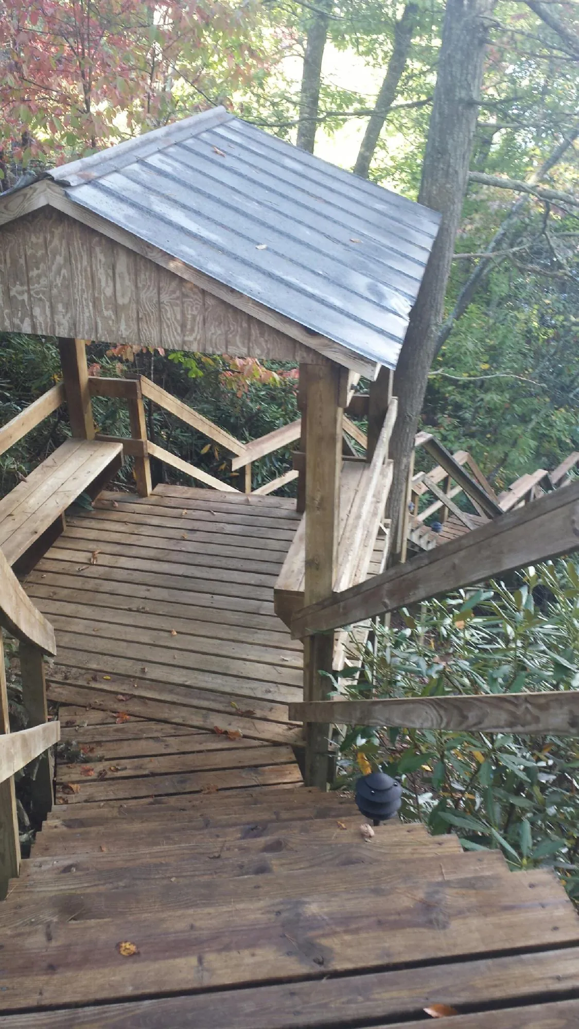 Metal roofed shelter over wooden steps on a wooded walkway — Skylight Repair & Installation work by our crew in Massapequa Park