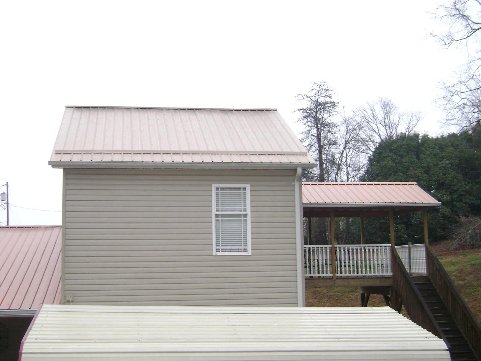 Tan metal roofs on a two story addition and attached porch, from a Roof Replacement job in Massapequa Park