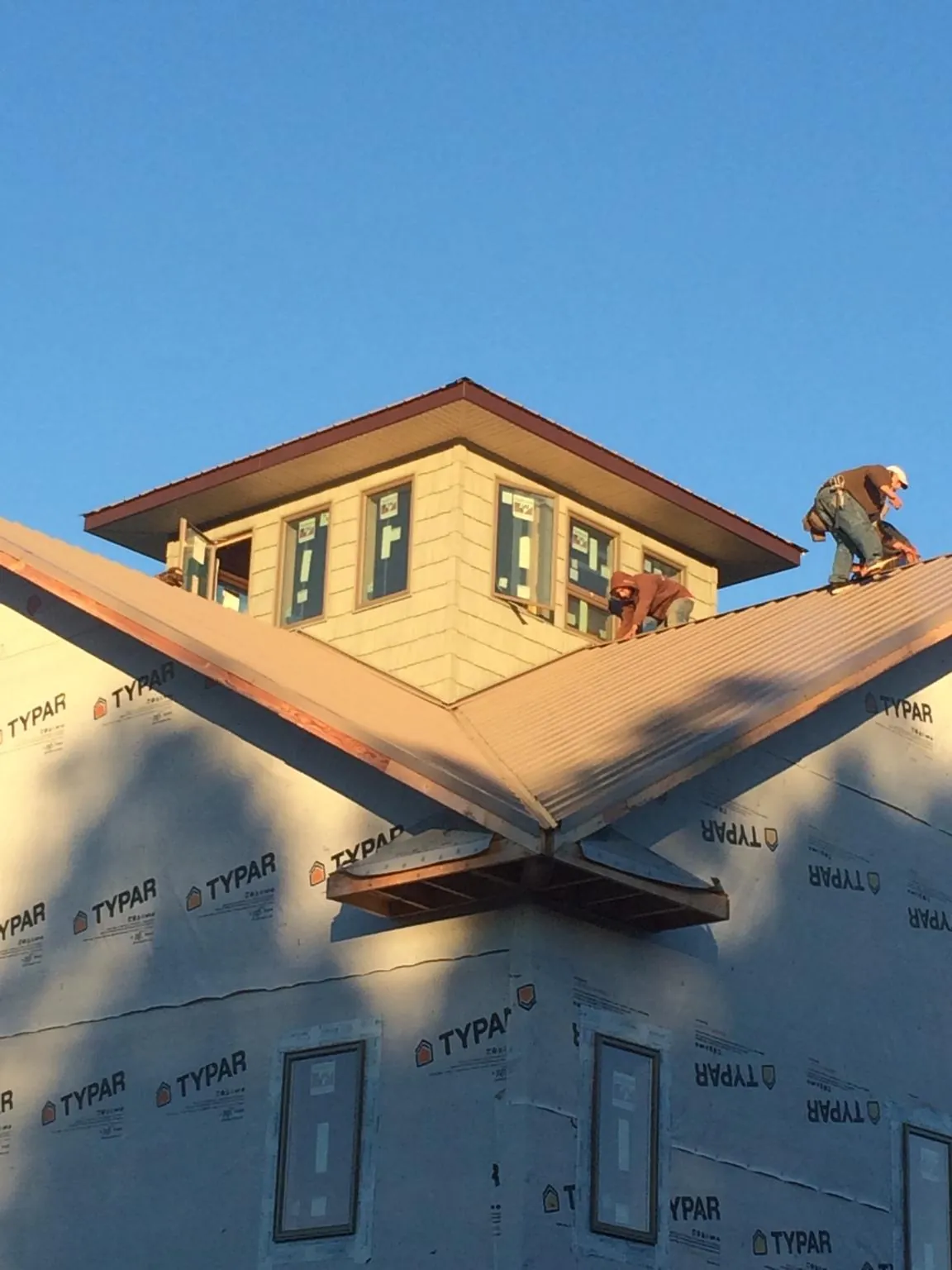 Roofers working around a rooftop cupola on a new metal roof at sunset — Roof Waterproofing in Massapequa Park by Roofing Brothers